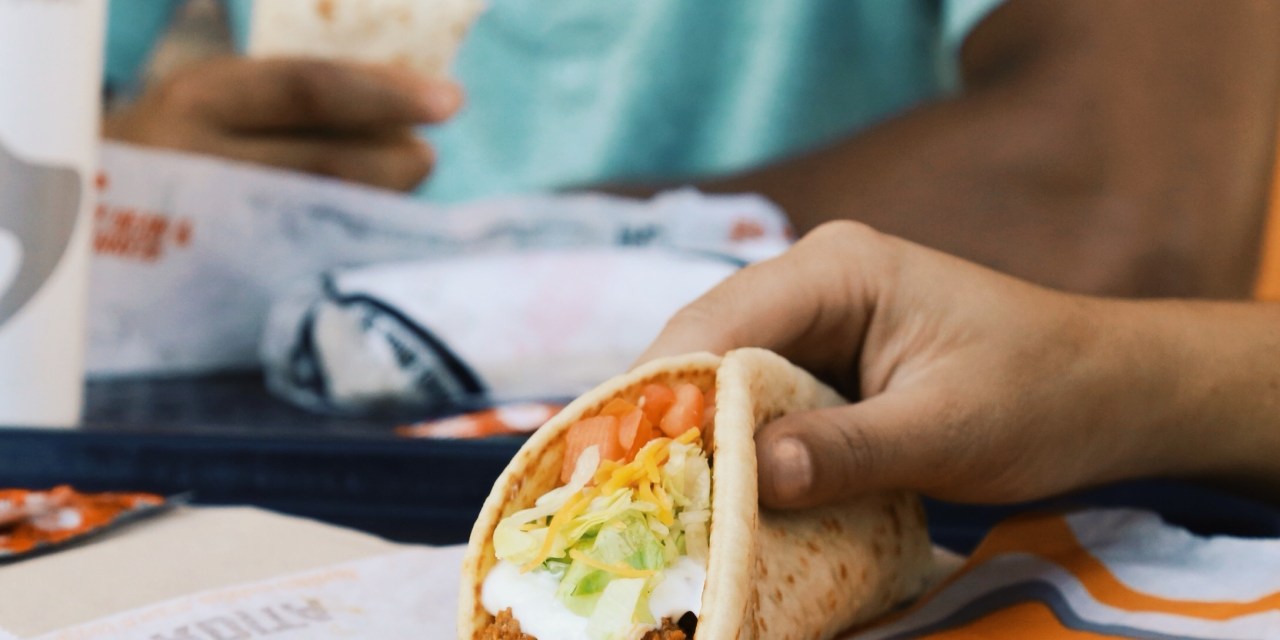 Photograph of a person holding a Taco Bell taco.