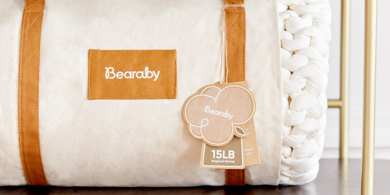 White Bearaby weighted blanket with tan straps on display in a store