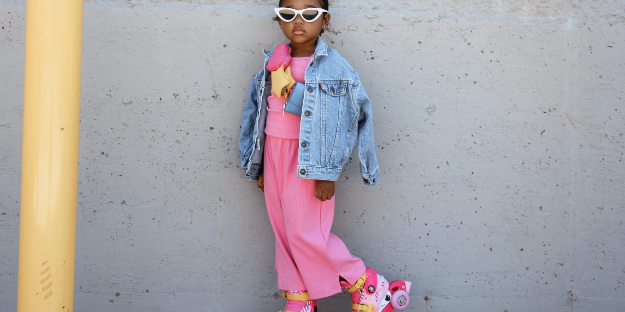 Kids clothing model in hot pink dress, jean jacket and sun glasses