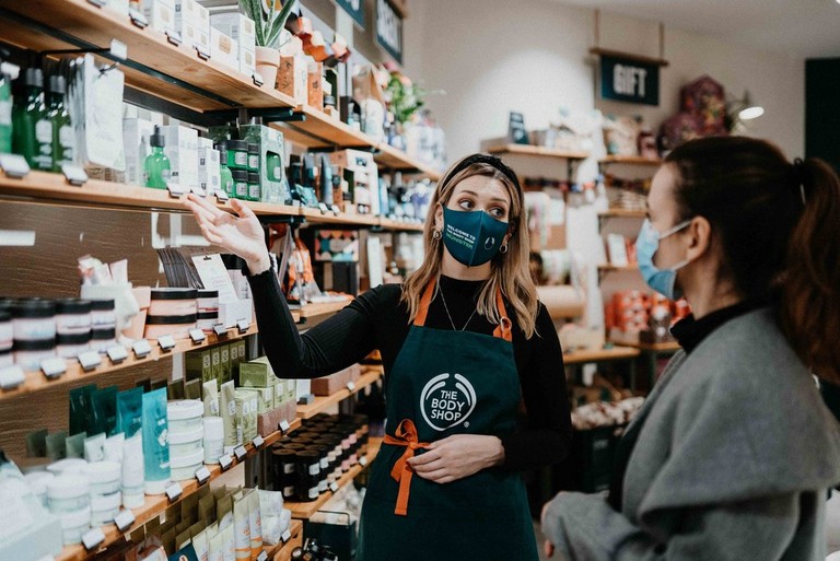 Employee showing off soap and other products at the Body Shop