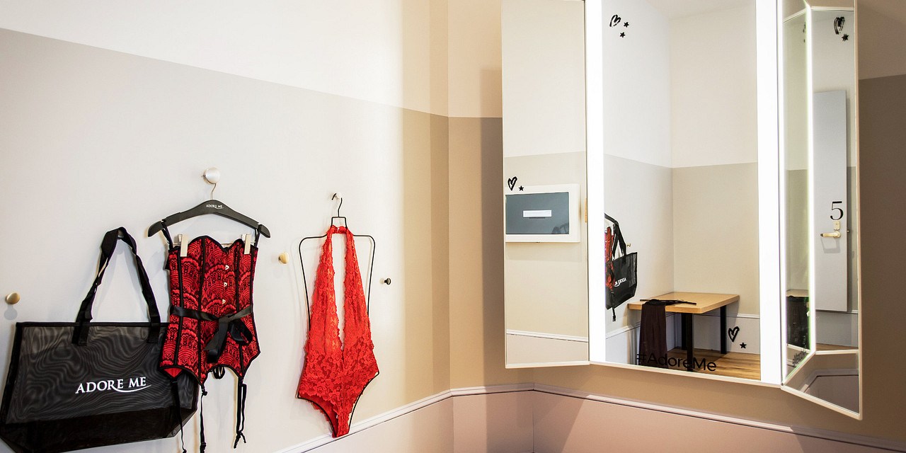 Store dressing room with mirror and lingerie hung up in the corner