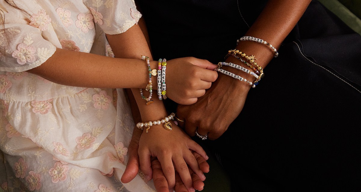 Models holding hands wearing charm bracelets